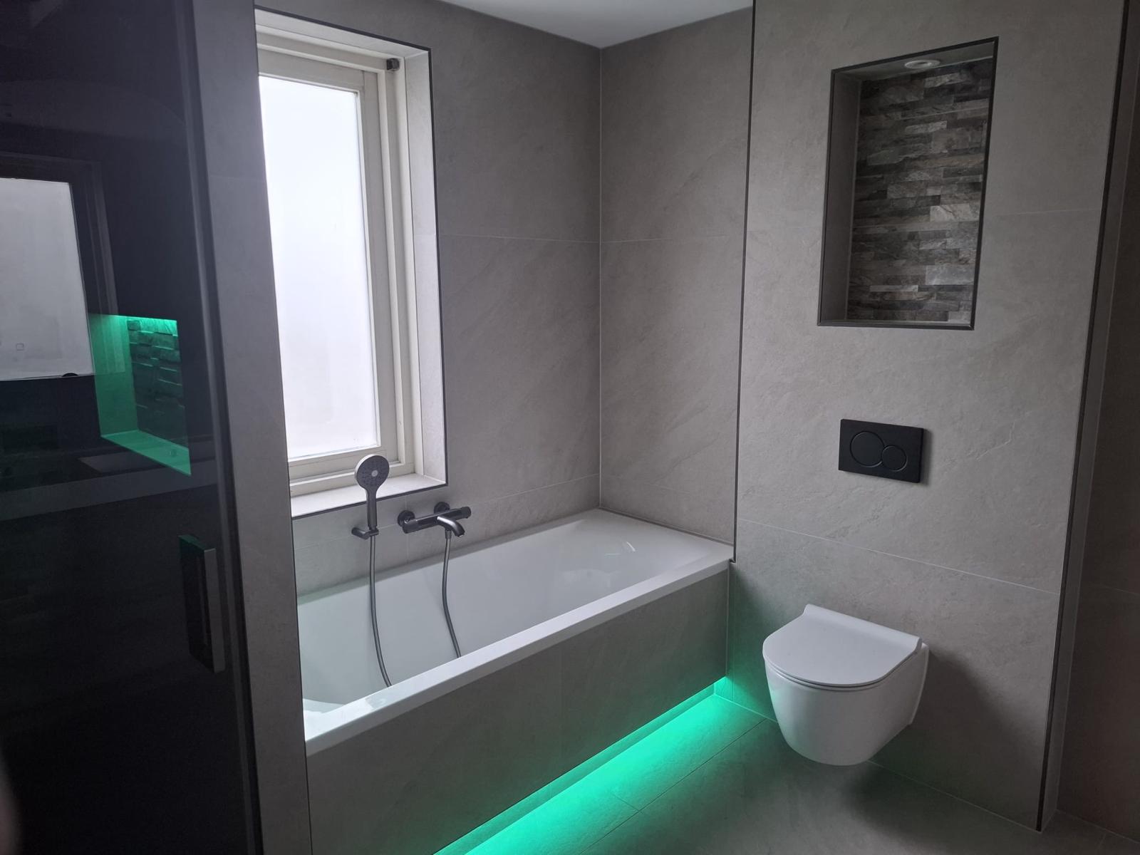 Badkamer met ligbad, hangtoilet en sfeerverlichting