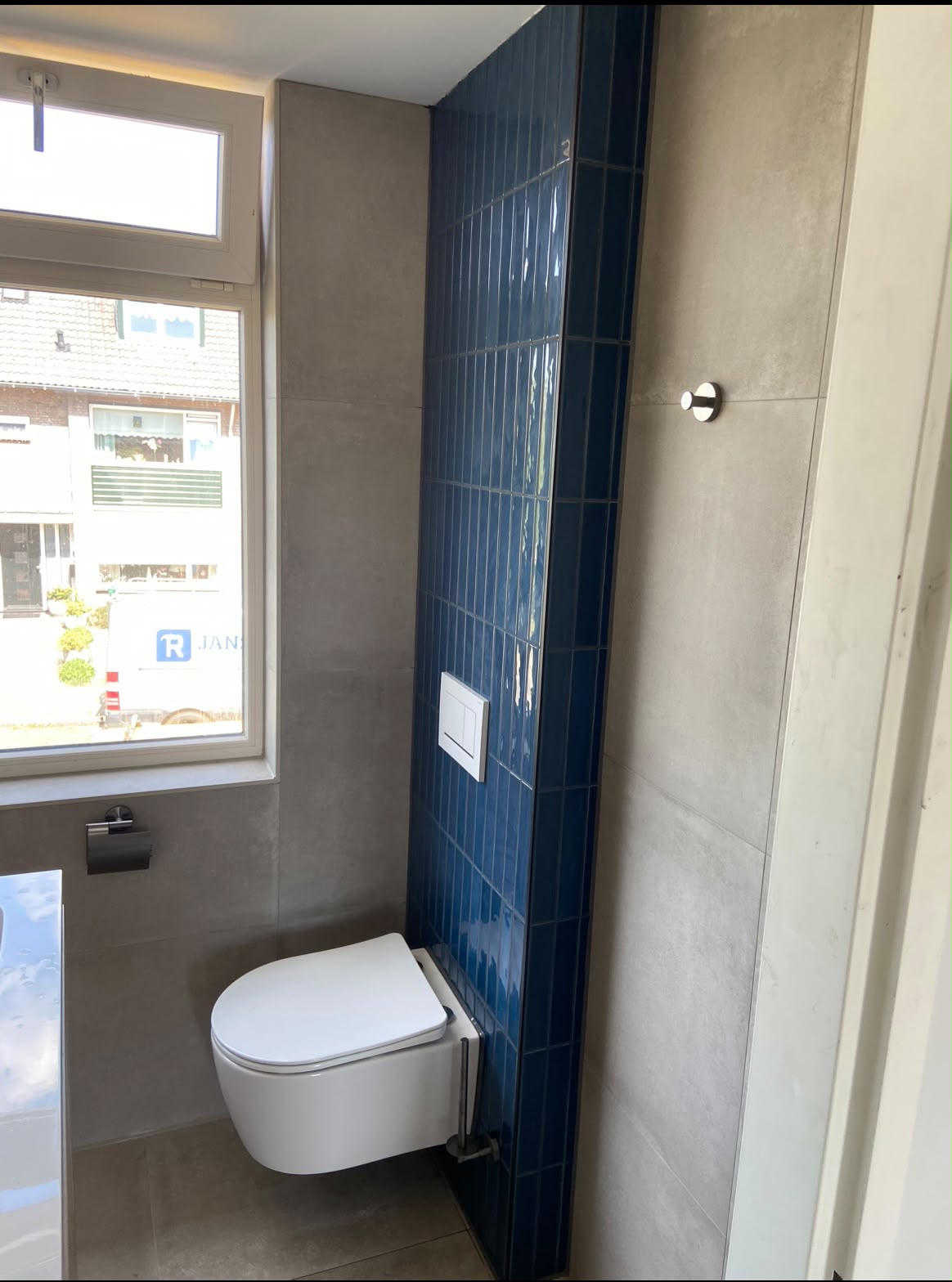 Hangtoilet tegen een blauw betegelde wand